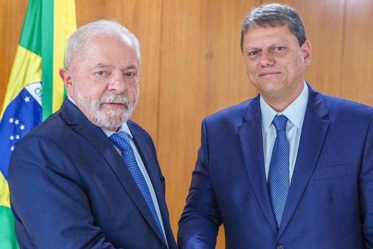 Lula cumprimenta Tarcísio no Palácio do Planalto. Eles vestem terno azul e aparecem da região da cintura para cima