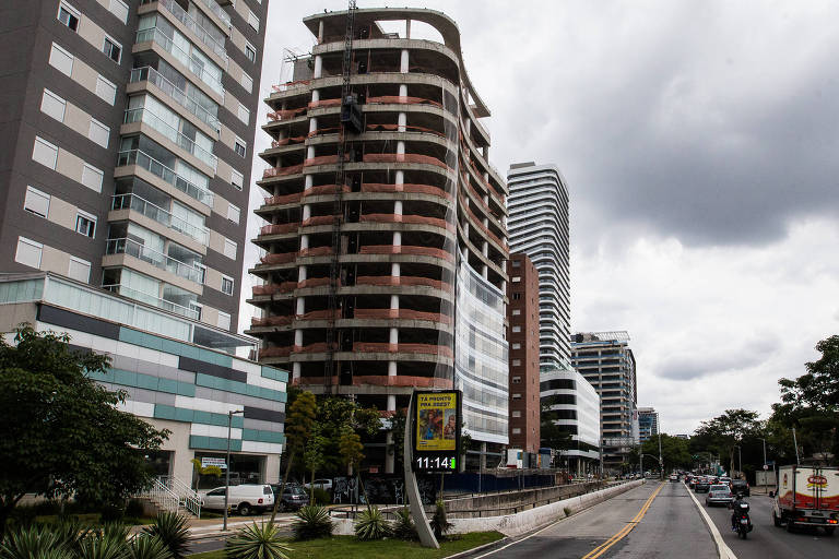 Prédios, um deles em construição, diante de avenida