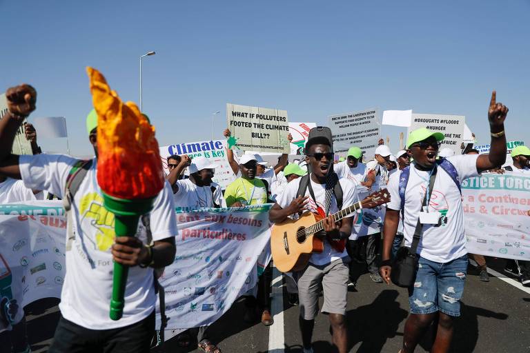 Homens negros protestam usando cartazes, violão, faixas e um objeto que imita uma tocha