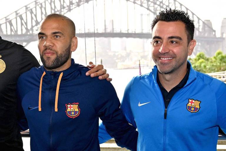 Imagem colorida mostra Daniel Alves, à esquerda, e o espanhol Xavi, à direita, ambos do tórax para cima