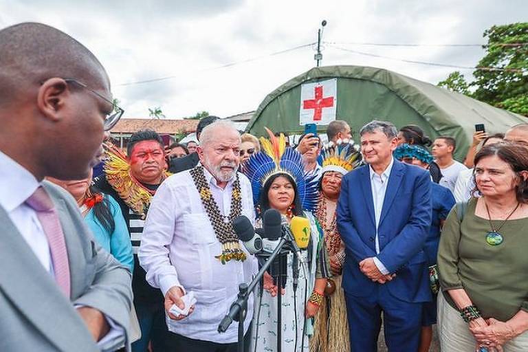 Lula faz pronunciamento com microfones apoiados em púlpito improvisado. usa camisa branca e tem ministros de ambos os lados