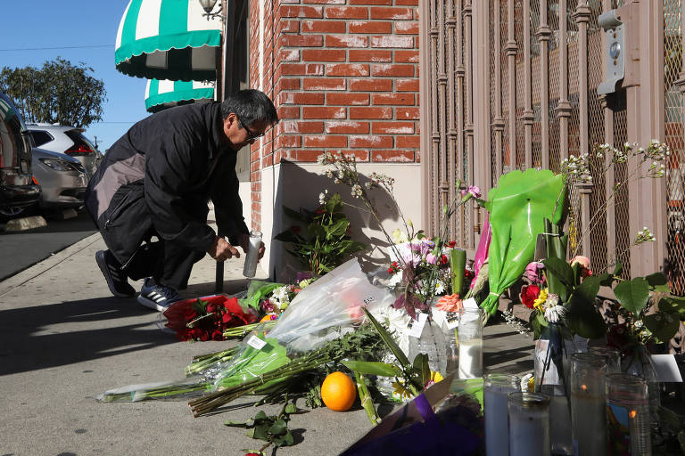 Homem coloca vela em homenagem às vítimas na entrada de boate em Monterey Park, Califórnia