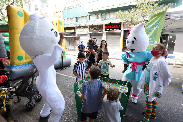 dois bonecos de zé gotinha com crianças e jogo de totó na rua