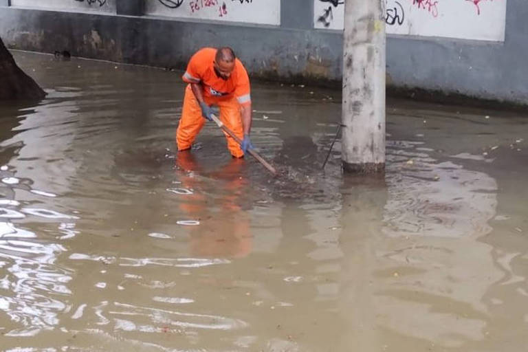 Gari desentope bueiro em rua alagada no Rio