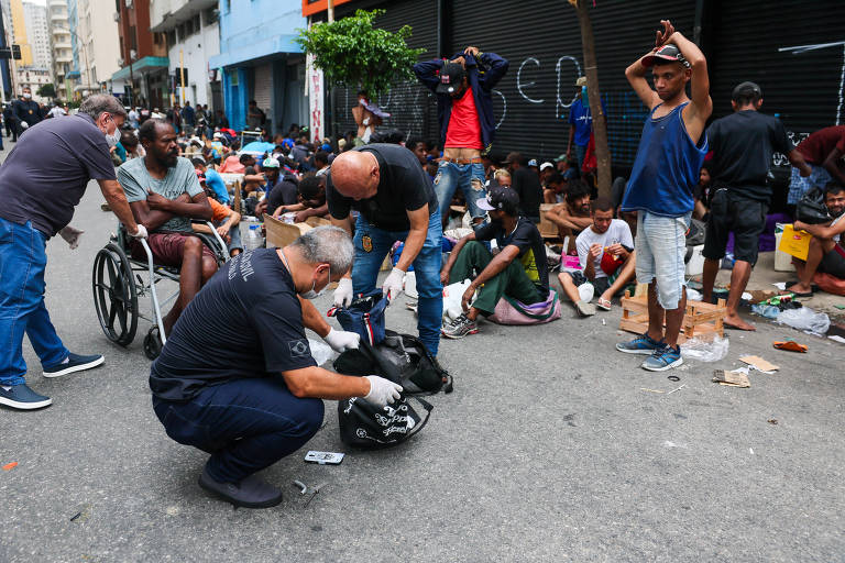 Policiais vistoriam pertences de pessoas em situação de rua, na região central de São Paulo, em local que ficou conhecido como Cracolândia, pela cena de consumo de entorpecentes ao ar livre.