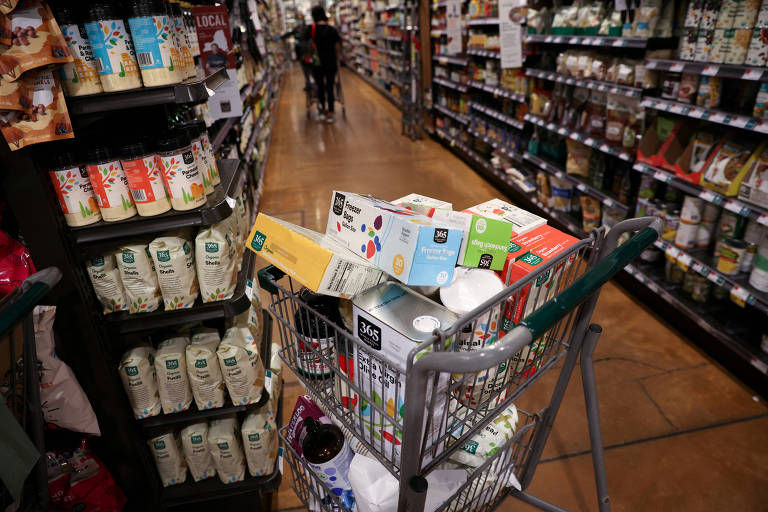 Carrinho lotado de compras ao lado de pratelerias