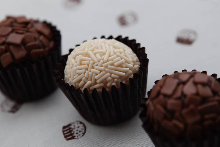 Foto mostra três brigadeiros, dois de chocolate e um de coco