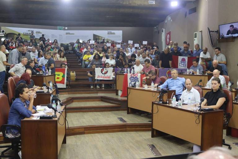 sessão da Câmara de Caxias do Sul com manifestantes ao fundo