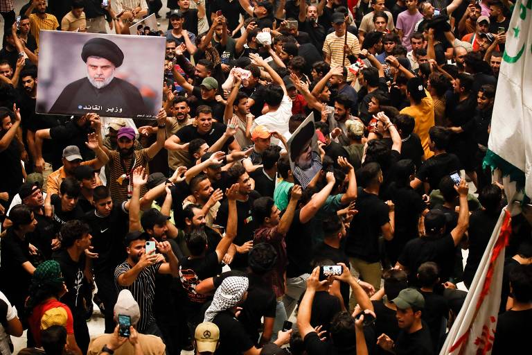 Apoiadores do clérigo Moqtada al-Sadr, no cartaz com turbante preto, invadem o Parlamento do Iraque durante a crise de poder no ano passado 