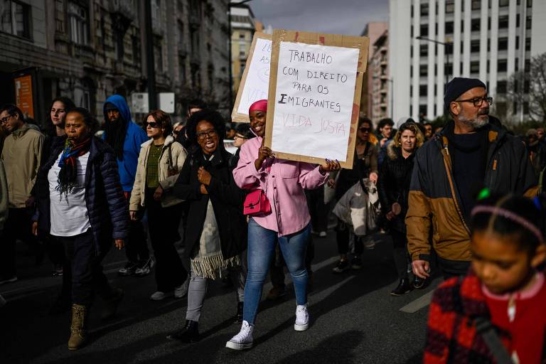 Manifestante pede direitos trabalhistas para imigrantes durante ato contra o aumento dos custos de moradia em Portugal, em Lisboa