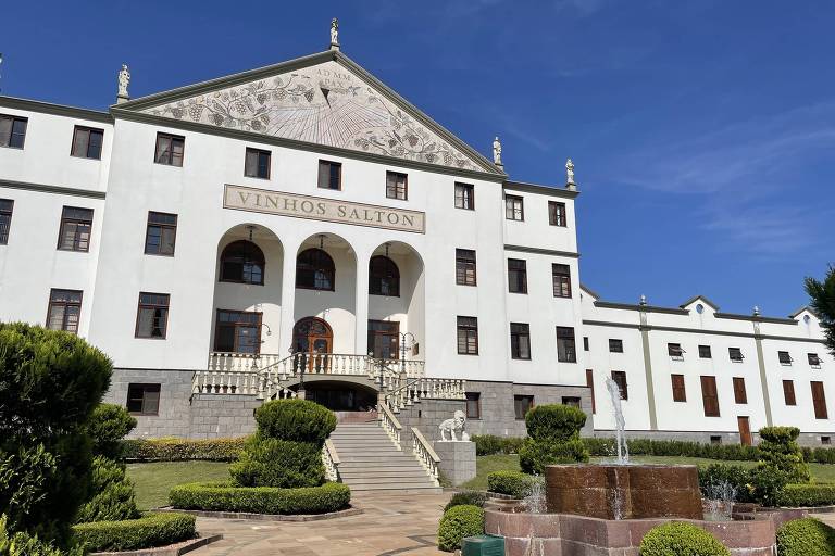 Casa suntuosa com jardins sob o céu azul com dizeres "vinícola salton"