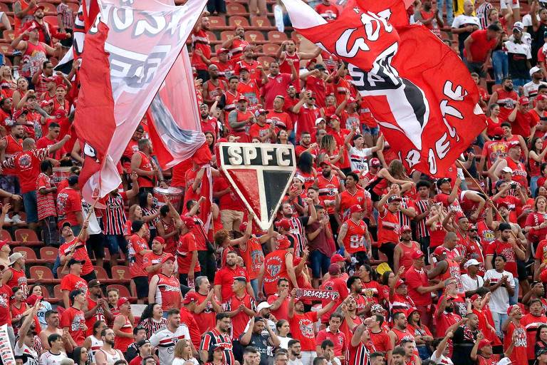 Torcedores do São Paulo lotam arquibancada, com bandeiras e o símbolo do clube no centro