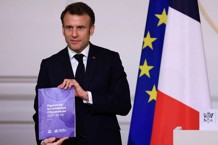 O presidente francês, Emmanuel Macron, posa no Palácio do Eliseu, em Paris, com documento sobre cuidados paliativos feito por um painel de cidadãos