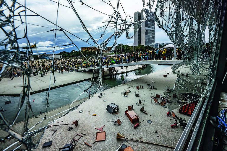 Vândalos golpistas invandem a praça dos Três Poderes e depredam os prédios; na imagem, vidraça do Palácio do Planalto quebrada