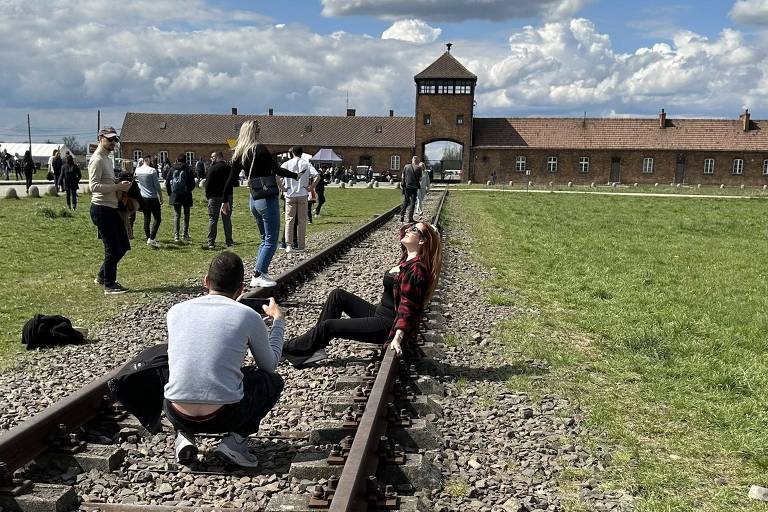 Mulher posa para foto em frente ao antigo campo de concentração de Auschwitz, na Polônia