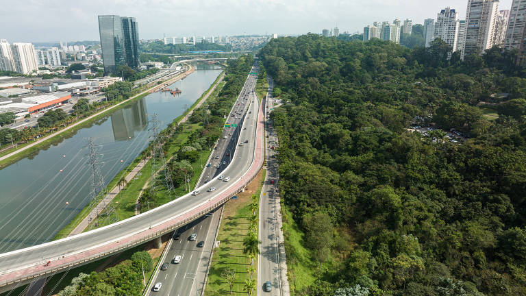 Vista aérea mostra o rio Pinheiros, à esquerda, com as pistas da via marginal fazendo a separação com a floresta, à direita