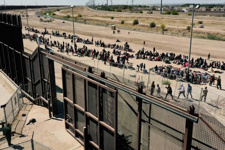 Migrantes aguardam na fronteira dos EUA com o México para se entregarem aos agentes da Patrulha de Fronteira