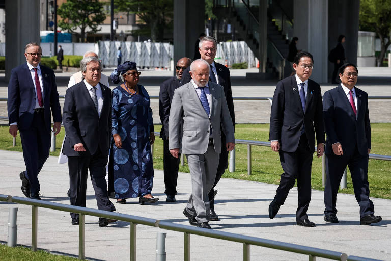 De terno cinza, o presidente Luiz Inácio Lula da Silva caminha em Hiroshima, no Japão, cercado por figuras como o premiê do Vietnã,  Pham Minh Chinh; o premiê do Japão, Fumio Kishida; o secretário-geral da OCDE, Mathias Cormann; o presidente de Comoros, Azali Assoumani; o premiê da Índia, Narendra Modi; o secretário-geral da ONU, António Guterres; e o premiê da Austrália, Anthony Albanese 