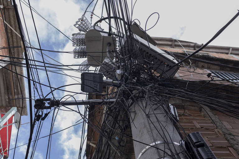 Na imagem, vários fios de ligações clandestinas saem de poste de luz