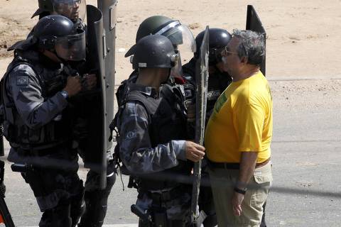 País em Protesto: manifestante encara a tropa da polícia nos arredores do estádio do Castelão, antes da partida entre a Seleção da Espanha contra Seleção da Itália, em jogo válido pela semifinal da Copa das Confederações, em Fortaleza (CE). Os manifestantes marcharam até uma barreira policial que impedia o acesso ao estádio e, por volta das 14h, parte deles começou a atirar bombas caseiras, coquetéis molotov, pedras e paus nos policiais militares. A PM revidou com balas de borracha e bombas de gás lacrimogêneo.*** A man stands facing riot police holding shields before the Confederations Cup semi-final soccer match between Spain and Italy at the Estadio Castelao in Fortaleza June 27, 2013. REUTERS/Paulo Whitaker (BRAZIL  - Tags: SPORT SOCCER CIVIL UNREST)