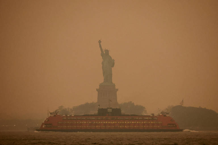 foto mostra estátua da liberdade vista atrás de fumaça causada por incêndio