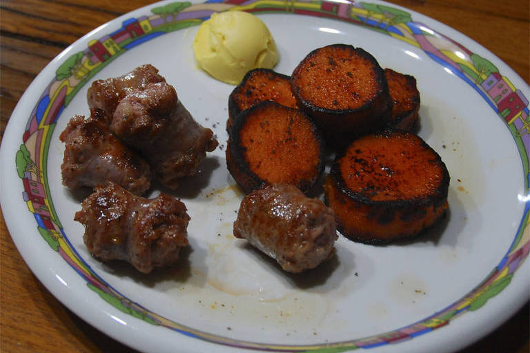 Prato de comida com linguiça, batata doce e uma bola de manteiga