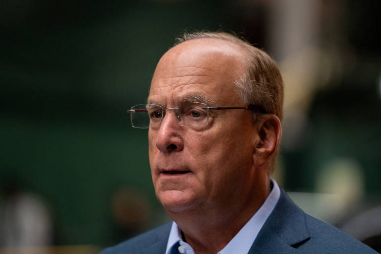 LArry Fink é um homem branco, calvo. Ele usa óculos e terno.