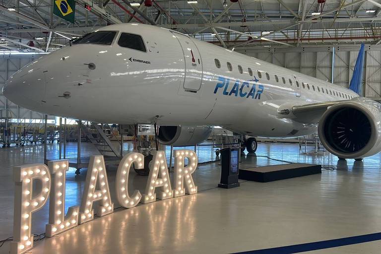 Avião branco, com a inscrição Placar na lateral, em um hangar