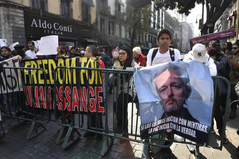 Protestantes mexicanos seguram cartazes em defesa de Julian Assange. Um cartaz possui a fotografia do jornalista com os dizeres em espanhol: se guerras iniciam com mentiras, a paz se inicia com a verdade. À esquerda desse cartas, um outro manifestante segura uma faixa com os dizeres em inglês: liberdade para Julian Assange