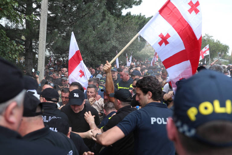 Grupo de invasores, formado por homens vestidos de preto carregando a bandeira da Geórgia, entra em conflito com a polícia 

