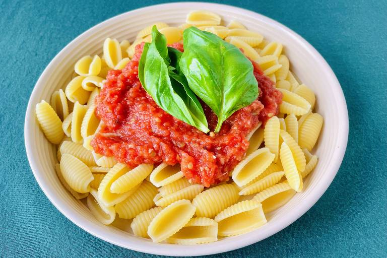 Macarrão em concha com molho de tomate com folhas de rúcula