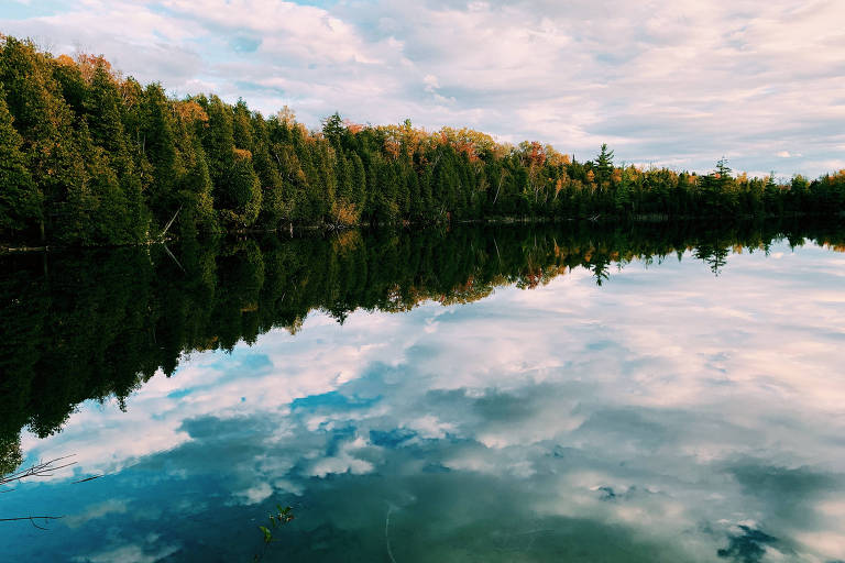 Lago com água refletindo o céu e as nuvens