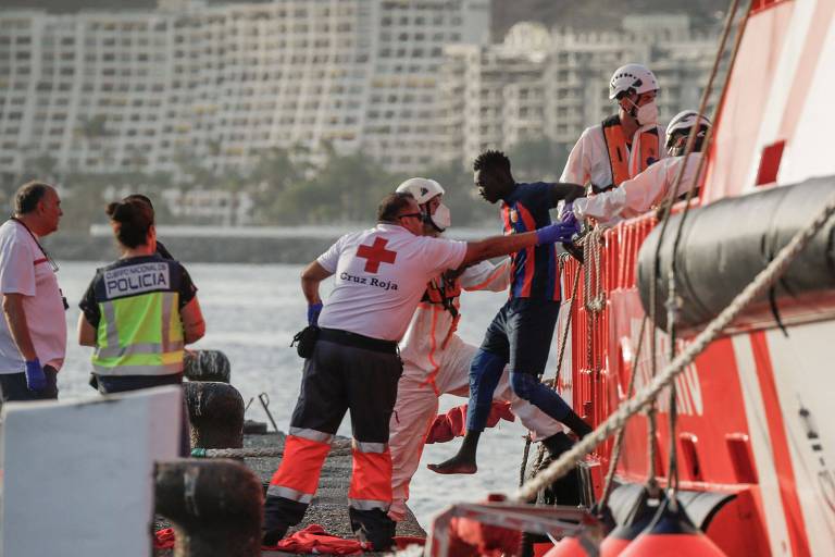 Cruz Vermelha ajuda imigrantes a desembarcar de barco da Guarda Costeira espanhola em porto de Arguineguin, na Gran Canária
