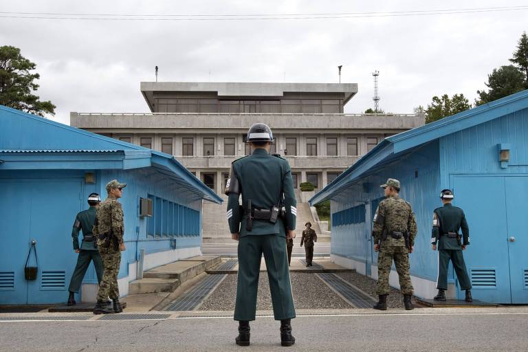 Soldados sul-coreanos (de costas) observam norte-coreanos se aproximarem nos prédios de negociação na fronteira entre os dois países, em Panmunjon (Sul)