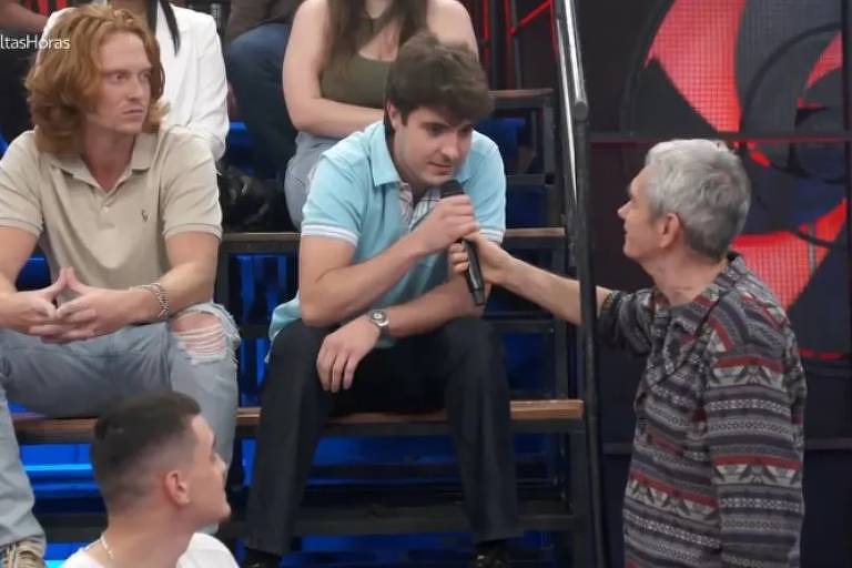 Em foto colorida, jovem de blusa verde aparece na plateia de programa de TV