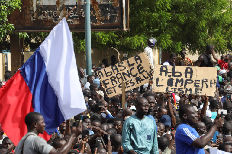 Manifestantes em apoio ao golpe militar no Níger levantam a bandeira da Rússia e placas em que se lê 'Abaixo a França e seus aliados' e 'Abaixo o imperialismo', em julho