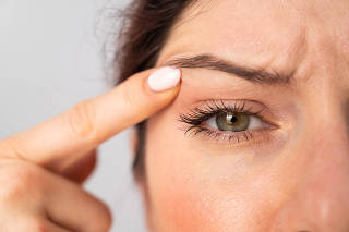 Close-up portrait of Caucasian middle-aged woman pointing to the wrinkles on the upper eyelid. Signs of aging on the face