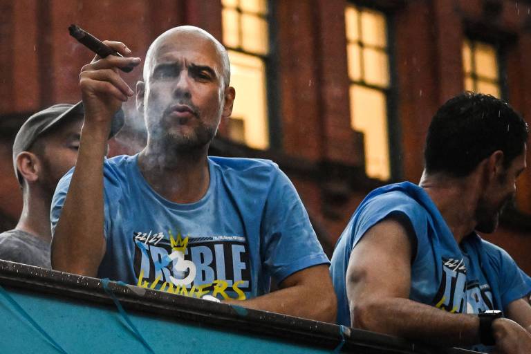 Pep Guardiola fuma charuto no topo do ônibus que levou os jogadores do Manchester City para comemorar o título europeu deste ano