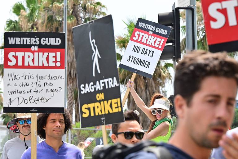 Integrantes de sindicatos de atores e de roteiristas protestam do lado de fora da sede da Netflix, na Califórnia