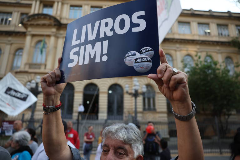 Manifestante homem levanta cartaz com os dizeres "Livros sim!" durante protesto de professores