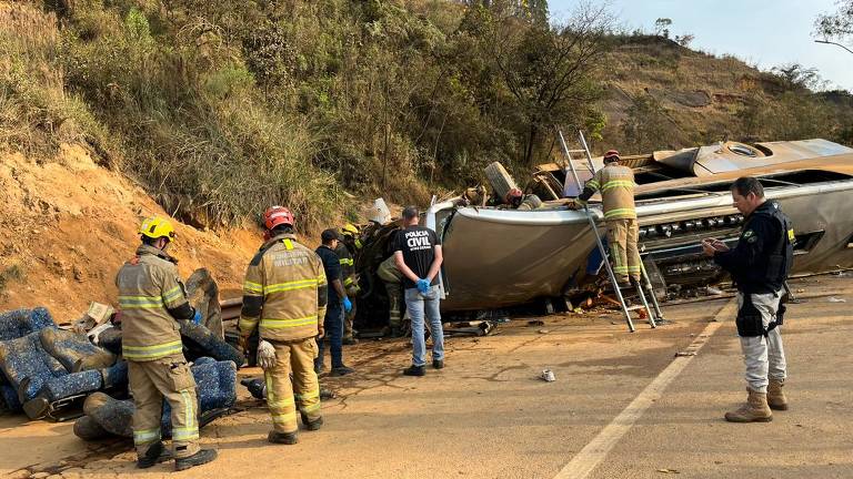 Equipes de resgate trabalhando no ônibus capotado à beira da rodovia