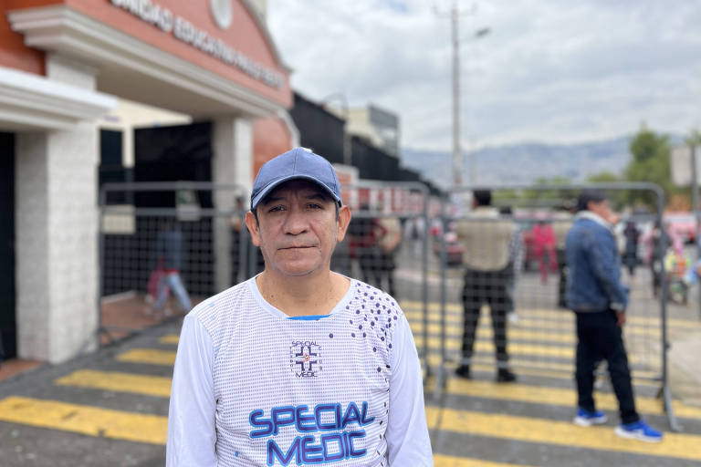 Homem de branco posa em frente a escola