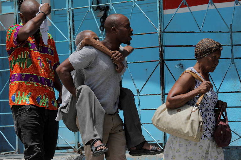 Homem carrega idoso ao fugir de bairro recentemente dominado por gangues em Porto Príncipe, capital do Haiti, em agosto