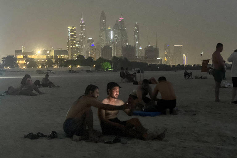 Pessoas na faixa de areia da praia em Dubai. Cenário noturno