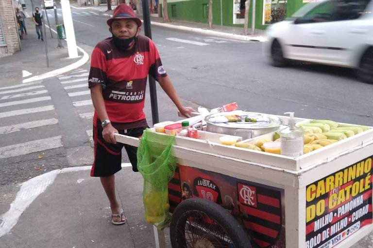 Homem com a roupa do flamengo segura um carrinho de milho