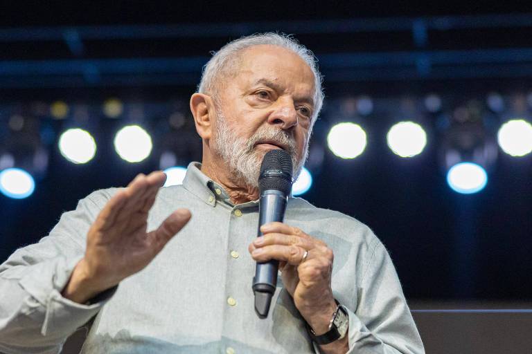 Lula, um homem branco de cabelos brancos, fala ao microfone em evento.