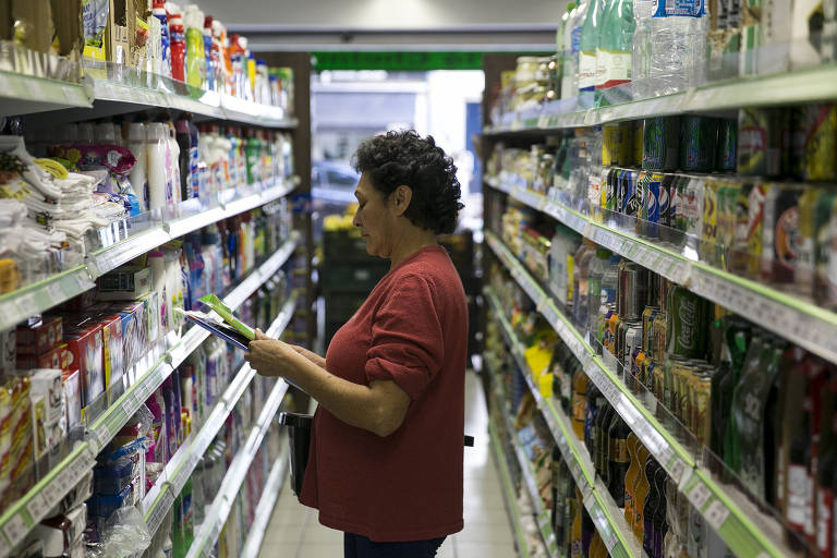 Mulher pesquisa preço de produtos em supermercado