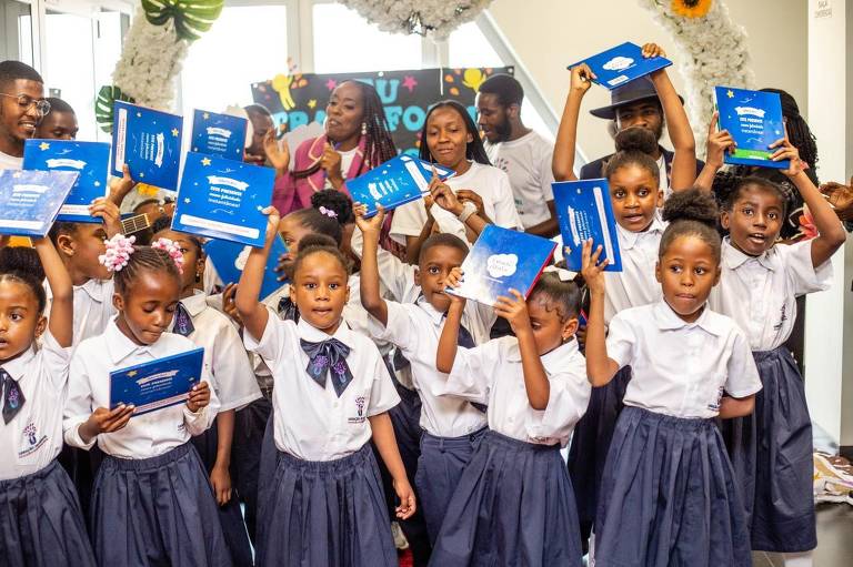 Grupode cerca de 20 crianças angolanas posam para foto; cada uma segurando seu livro autoral
