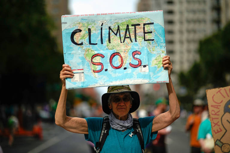 Homem segura cartaz com o mapa-múndi em um pedido de socorro contra as mudanças climáticas; protestos marcaram o início da Semana do Clima em Nova York