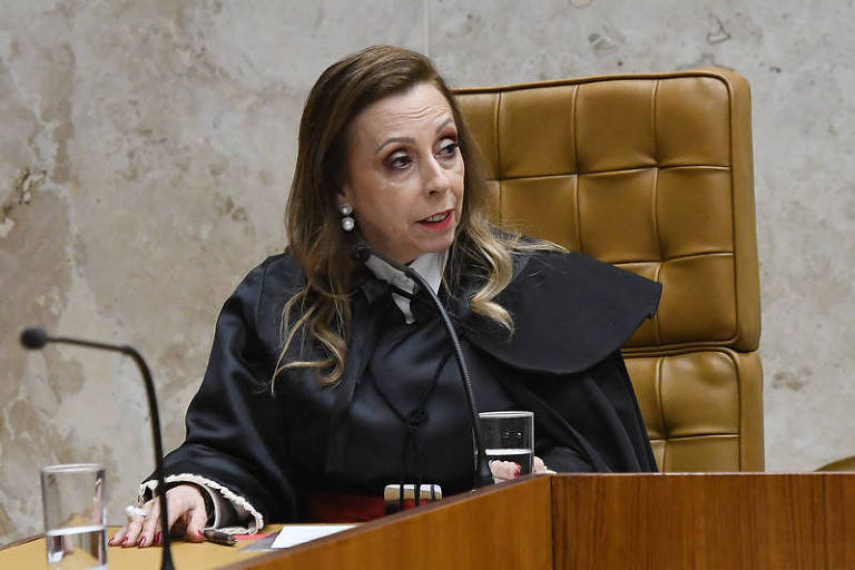 Elizeta, uma mulher branca, cabelos longos, castanhos claros com mechas loiras, vestida de toga preta. Ela está sentada em uma poltrona bege, na bancada do plenário do STF